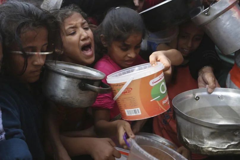 Palestinians line up for food during the ongoing Israeli bombardment of the Gaza Strip in Rafah on Monday, November 13, 2023.