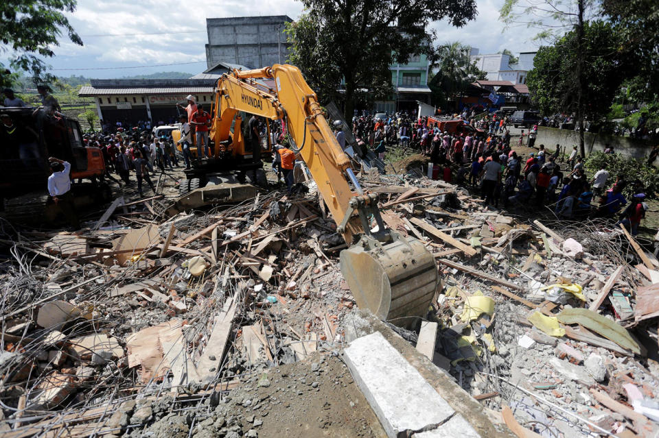 Rescue workers use heavy equipment to search for victims