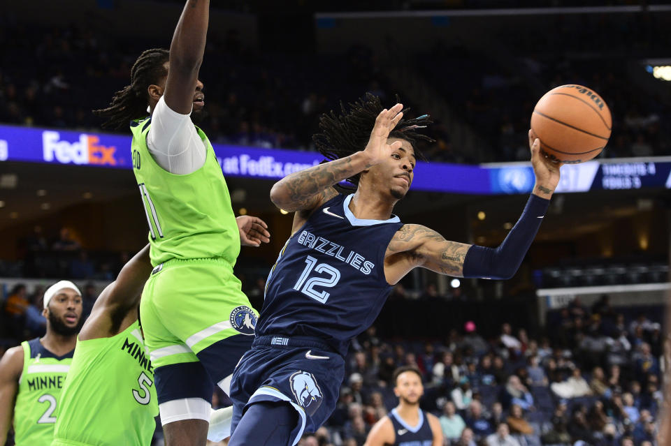 Memphis Grizzlies guard Ja Morant (12) passes the ball ahead of Minnesota Timberwolves center Naz Reid (11) in the second half of an NBA basketball game Monday, Nov. 8, 2021, in Memphis, Tenn. (AP Photo/Brandon Dill)