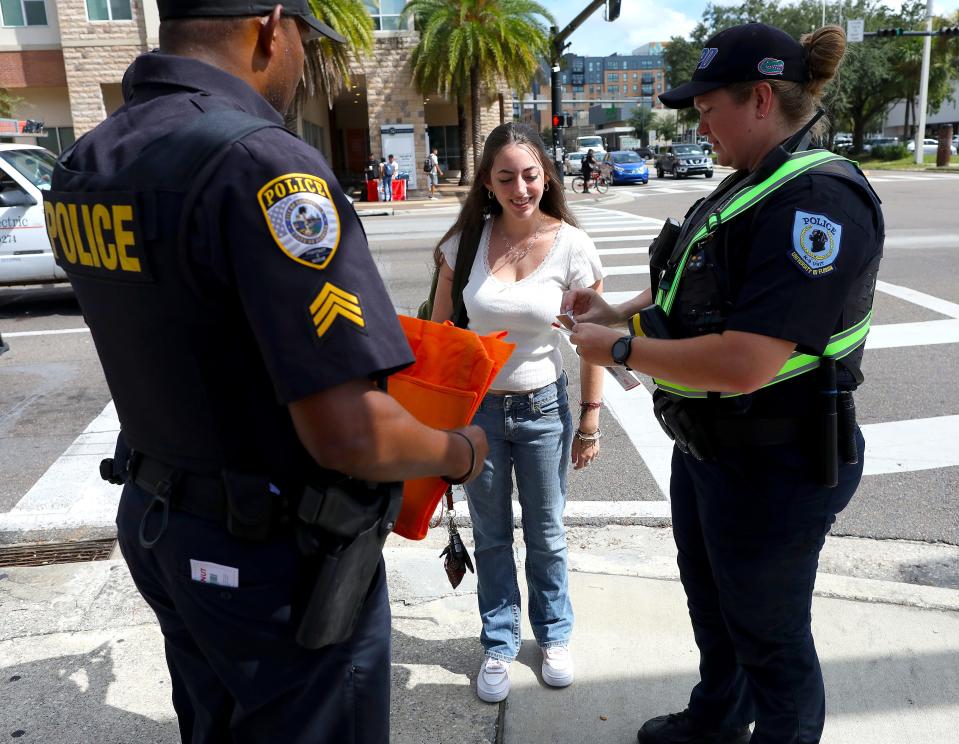 University of Florida police and Gainesville police talk with a UF student about street safety at the intersection of University Avenue and 13th Street in Gainesville FL. August 24, 2022. UF and the FDOT are partnering with each other, as the Fall semester of classes begins, to bring awareness to the need for pedestrian safety along the borders of UF.