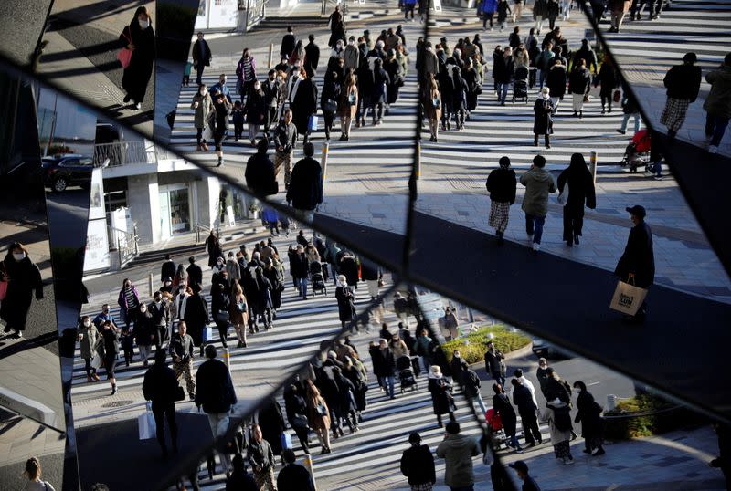 FILE PHOTO: Year-end shoppers wearing protective face masks are reflected on mirrors at a shopping and amusement district, amid the coronavirus disease (COVID-19) outbreak, in Tokyo