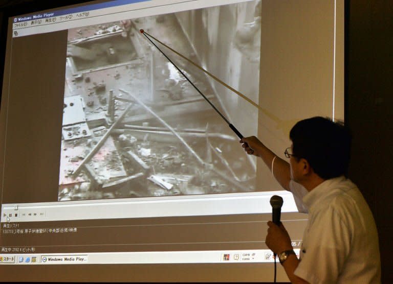 Masayuki Ono, acting head of Tokyo Electric Power Co (TEPCO) nuclear power and facilities section, points at an image showing steam rising from the unit 3 reactor building at the Fukushima Dai-ichi nuclear plant, at a news conference at the company's headquarters in Tokyo on July 18, 2013. TEPCO insisted Thursday there was no sign of spiking radiation at the crippled facility despite the steam