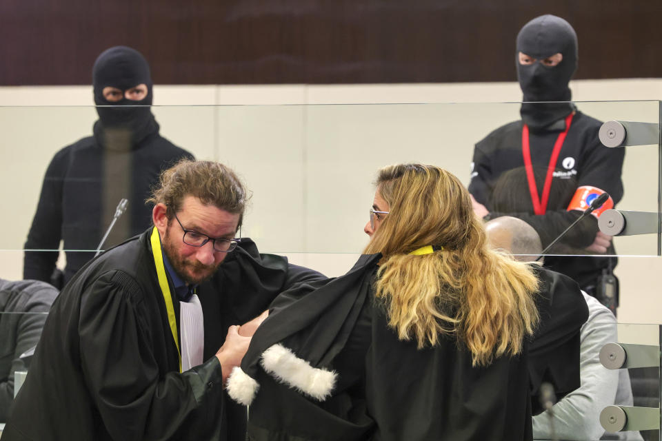 Lawyers speak with defendants through the glass of a specially designed glass box during the start of the trial for the Brussels attacks, that took place on March 22, 2016, at the Justitia building in Brussels, Monday, Dec. 5, 2022. More than six years later, ten defendants face charges including murder, attempted murder and membership, or participation in the acts of a terrorist group, over the morning rush hour attacks at Belgium's main airport and on the central commuter line on March, 22, 2016. (AP Photo/Olivier Matthys, Pool)