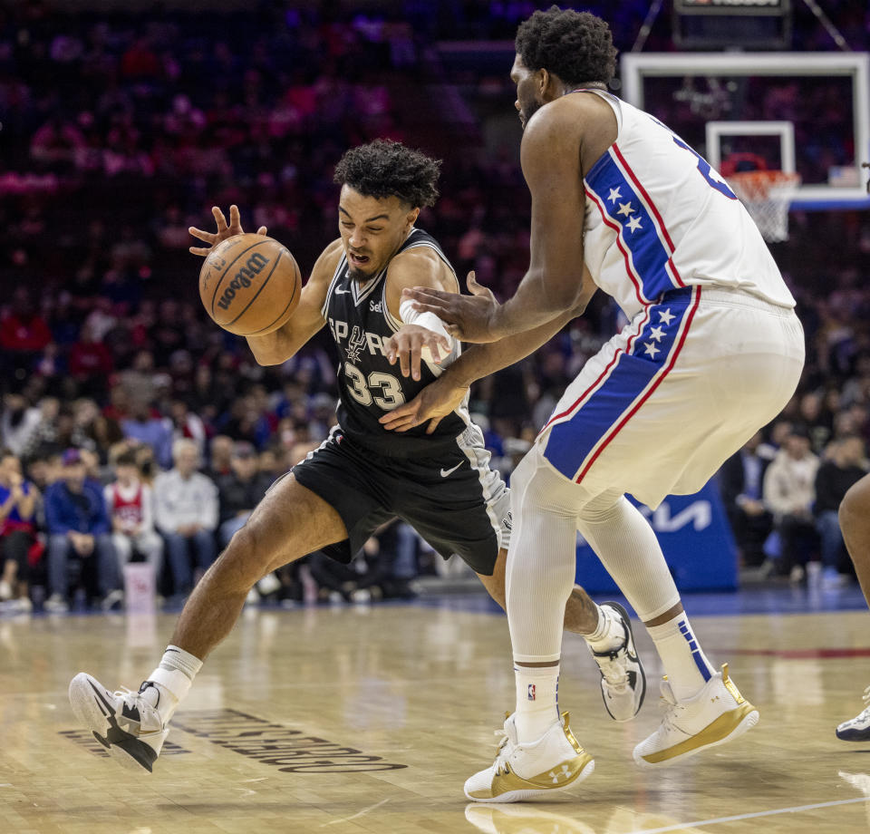 San Antonio Spurs guard Tre Jones (33) moves around Philadelphia 76ers center Joel Embiid (21) in the first half of an NBA basketball game, Saturday, Oct. 22, 2022, in Philadelphia. (AP Photo/Laurence Kesterson)