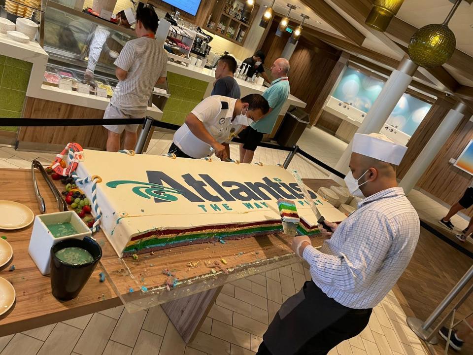 staff member slicing an atlantis cake with rainbow layers