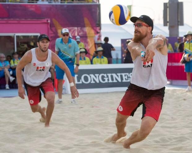 Canada's Samuel Pedlow, right, returns a shot as teammate Sam Schachter looks on during the beach volleyball final against Australia at the Commonwealth Games in 2018. (Ryan Remiorz/The Canadian Press - image credit)