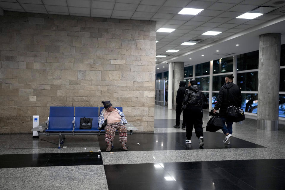 Teresa, who is homeless, sleeps on a seat at the Jorge Newbery international airport, commonly known as Aeroparque, in Buenos Aires, Argentina, Thursday, April 6, 2023. Despite the bustling activity of passengers, over 100 homeless people sleep at Aeroparque each night. (AP Photo/Natacha Pisarenko)