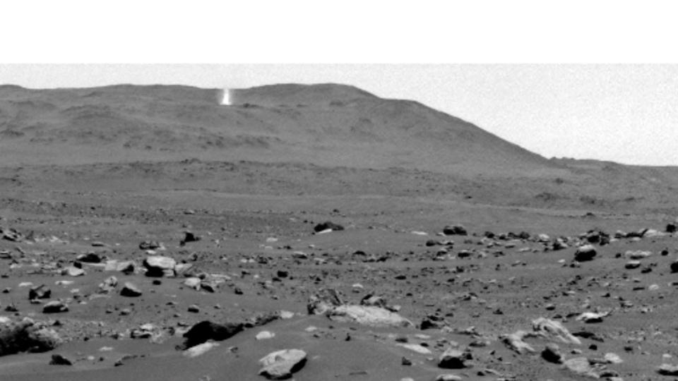 a dust devil churns on a barren, distant martian ridge