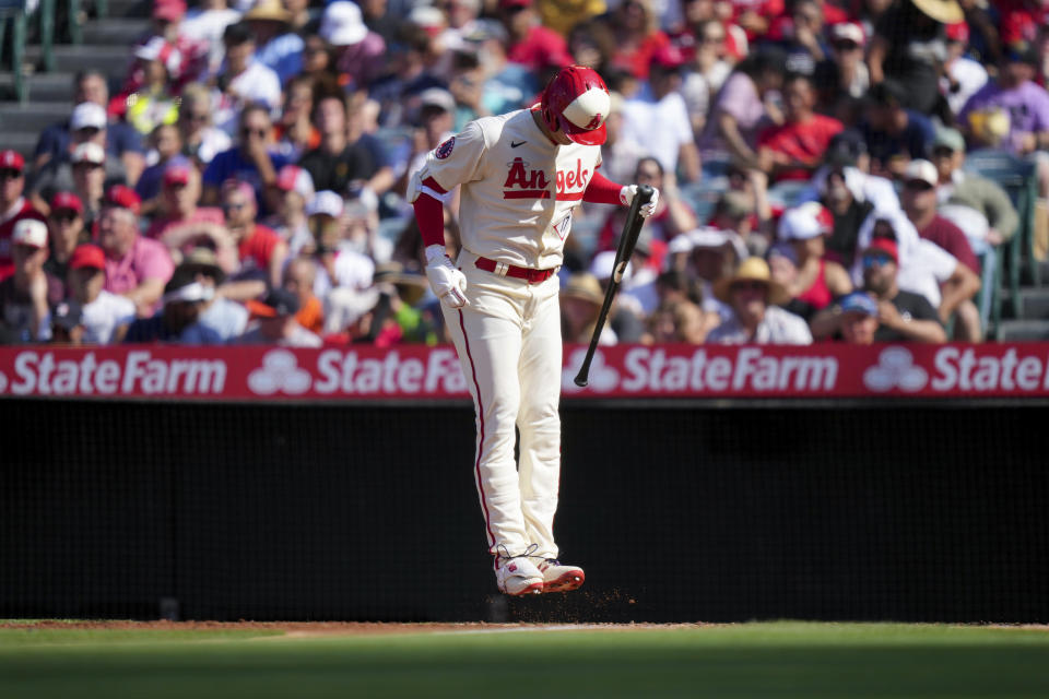 Los Angeles Angels designated hitter Shohei Ohtani cleans dirt from his cleats during the first inning of a baseball game against the Houston Astros in Anaheim, Calif., Sunday, July 16, 2023. (AP Photo/Eric Thayer)