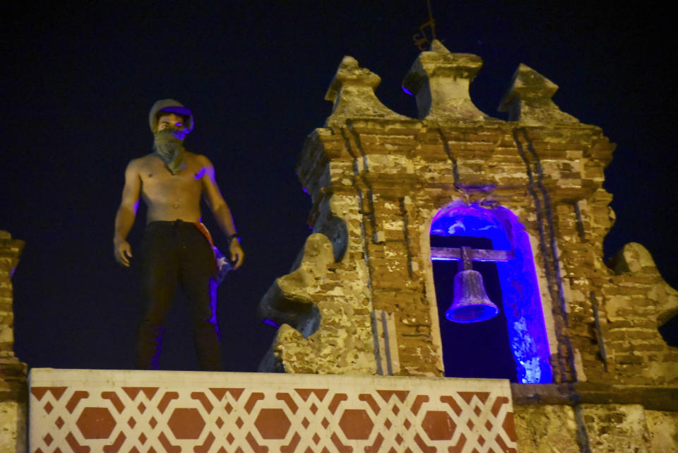 A demonstrator stands on the roof of a building during clashes in San Juan, Puerto Rico, Wednesday, July 17, 2019. Thousands of people marched to the governor's residence in San Juan on Wednesday chanting demands for Gov. Ricardo Rossello to resign after the leak of online chats that show him making misogynistic slurs and mocking his constituents. (AP Photo /Carlos Giusti)