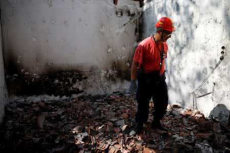 A member of a rescue team searches inside a destroyed house following a wildfire at the village of Mati, near Athens, Greece, July 25, 2018. REUTERS/Alkis Konstantinidis