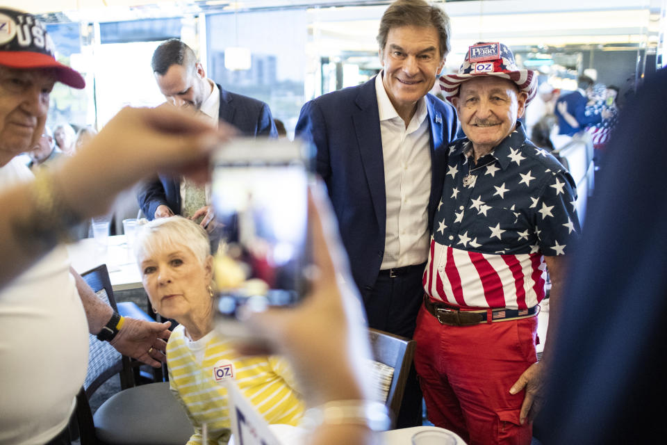 Republican nominee for U.S. Senate, Dr. Mehmet Oz, center, drops by The Capitol Diner, Friday, Aug. 12, 2022, in Swatara Township, Pa. (Sean Simmers/The Patriot-News via AP)