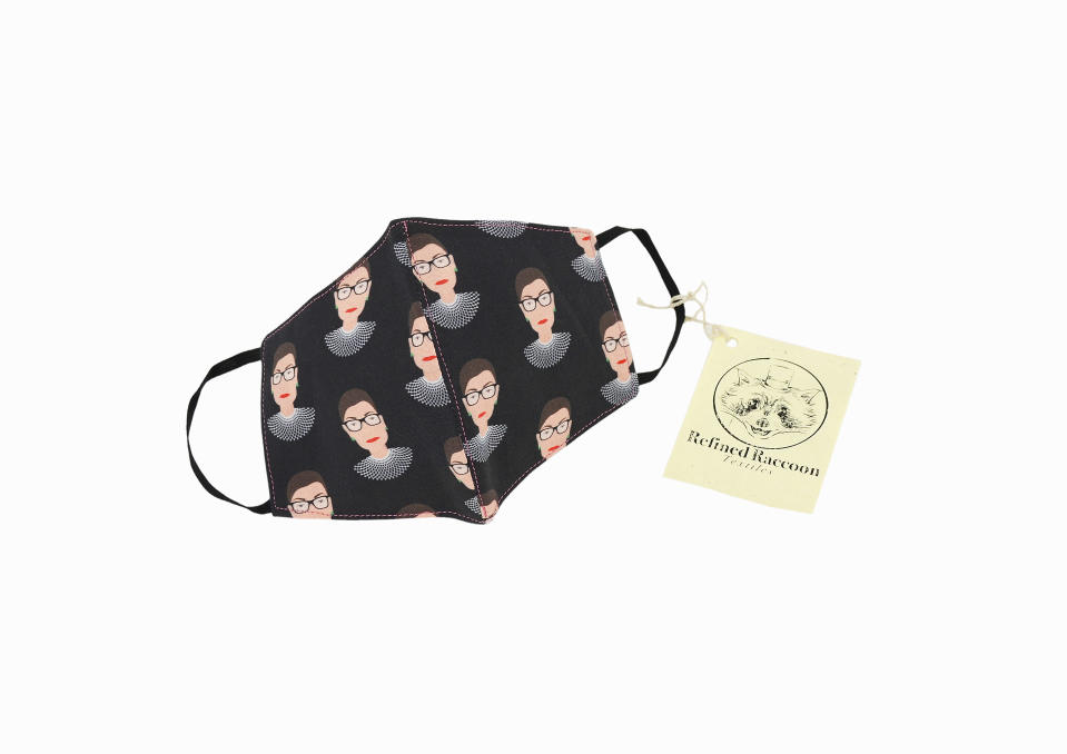 This product image released by Refined Raccoon Textiles shows a 100% cotton face mask featuring a repeating design of the late Supreme Court justice Ruth Bader Ginsburg's head against a black background. Ten percent of each purchase will be donated to the American Cancer Society in Ginsburg's honor. (Refined Raccoon Textiles via AP)