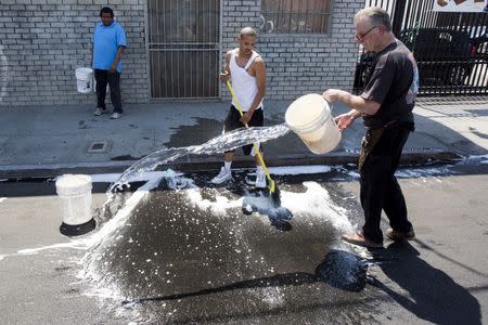 Crews clean the street where 3 children were found dead in a parked vehicle in Los Angeles, California September 9, 2015. REUTERS/Jonathan Alcorn