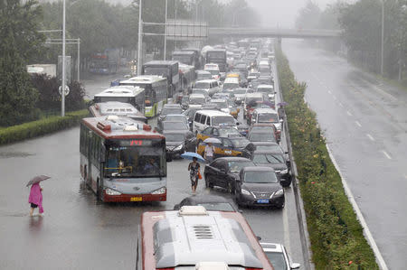 Vehicles are trapped on a flooded street during a heavy rainfall in Beijing, China, July 20, 2016. China Daily/via REUTERS