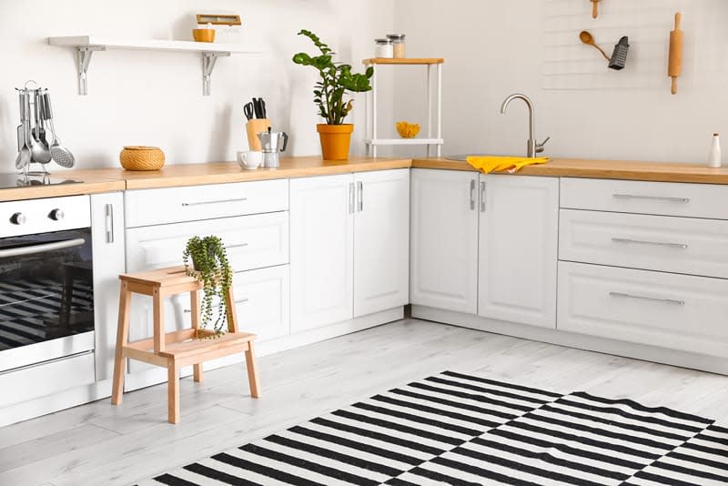 Interior of modern kitchen with white counters and wooden step stool