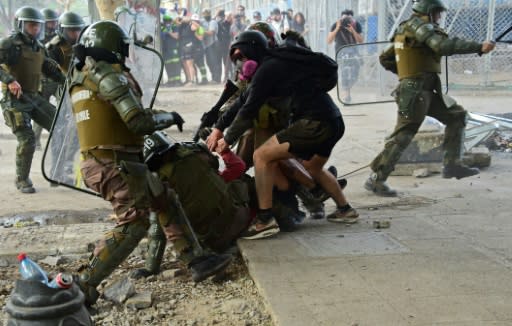 Demonstrators struggle with riot police during a protest in Santiago