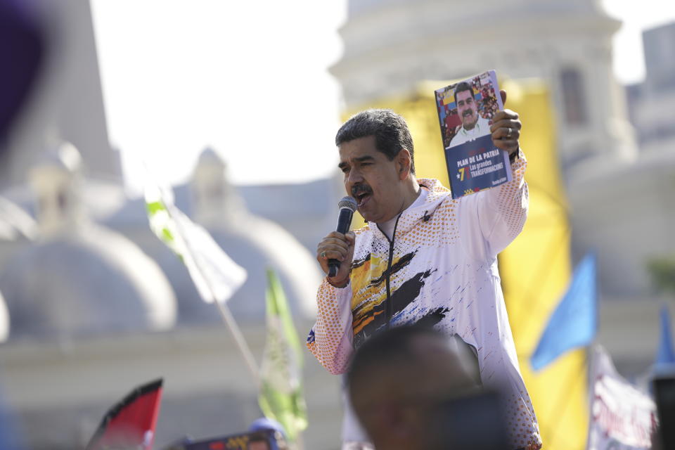 Venezuelan President Nicolas Maduro holds up a book featuring his photo at the Spanish title: 2025 - 2031. Plan of the Homeland. Big Transformations" as he speaks to supporters after registering his candidacy to run for reelection at the National Election Commission (CNE) in Caracas, Venezuela, Monday, March 25, 2024. Elections are set for July 28. (AP Photo/Matias Delacroix)