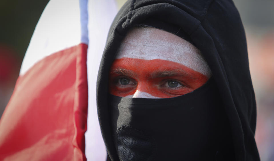 Holding an old Belarusian national flag a protester attends an opposition rally in Minsk, Belarus, Sunday, Oct. 4, 2020. Hundreds of thousands of Belarusians have been protesting since the Aug. 9 presidential election. (AP Photo)