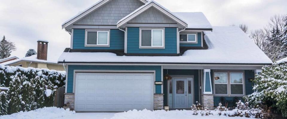 Family house with front yard in snow. Residential house on winter cloudy day