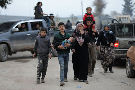 A kurdish boy holds his baby brother, as he walks with his family in Afrin, Syria March 18, 2018. REUTERS/Khalil Ashawi