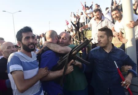 A plain clothes policeman is hugged by people as they celebrate the surrendering of the soldiers involved in the coup on the Bosphorus Bridge in Istanbul, Turkey July 16, 2016. REUTERS/Yagiz Karahan