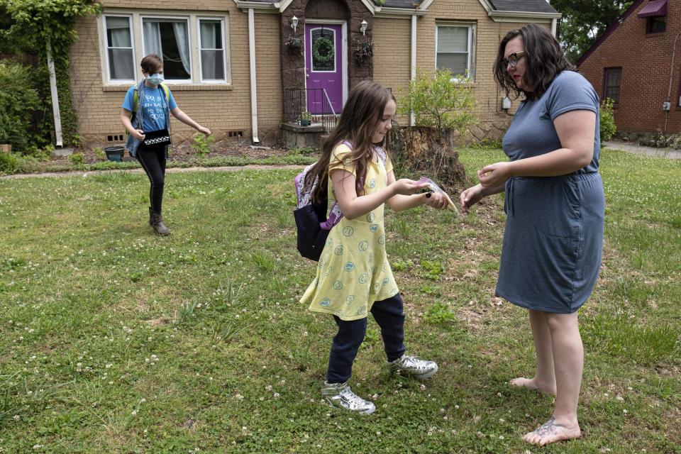 Abby Norman greets her daughters Juliet, 11, left, and Priscilla, 9, as they arrive home from school to the family's Decatur, Ga., home on Tuesday, May 18, 2021. Priscilla was in tears the first morning of testing this year because she felt pressure to do well, but didn't feel prepared after remote learning. (AP Photo/Ben Gray)