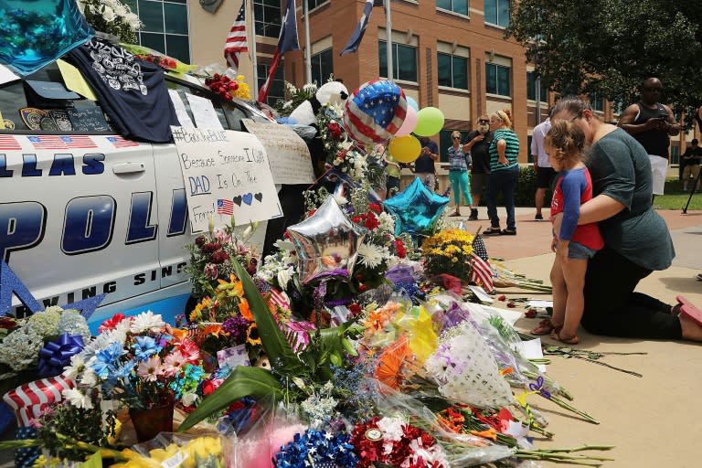 People visit a growing memorial at the Dallas police department's headquarters near the active crime scene in downtown Dallas, Texas on July 9, 2016
