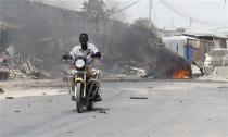 A motorcyclist rides away from the scene of an explosion near the entrance of the airport in Somalia's capital Mogadishu February 13, 2014. REUTERS/Feisal Omar