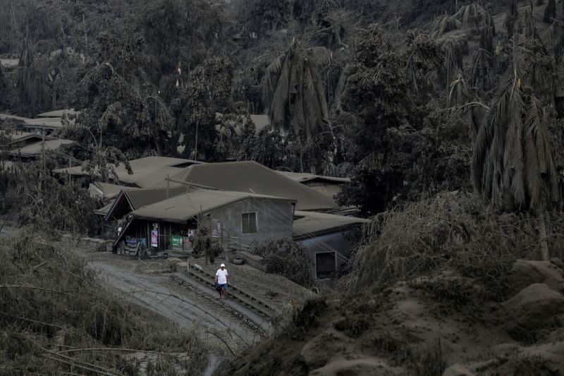 A man walks on a road covered with ashes from the erupting Taal Volcano in Talisay