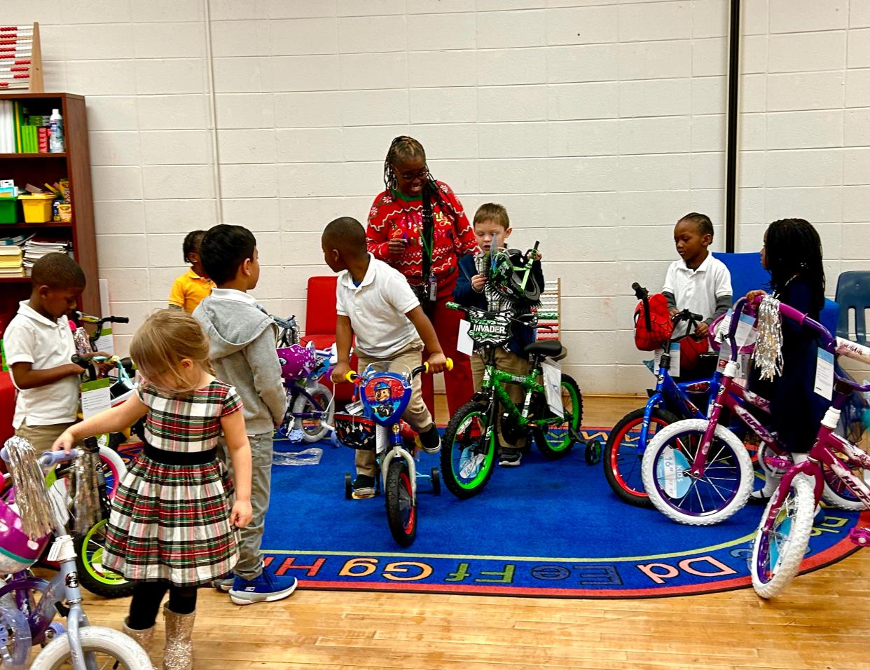 Early Learning Center at Henderson E. Formey School Principal, Erica Swindell-Foster helps Pre-K and Kindergarten students test out donated bikes from Gateway Terminals on Thursday Dec. 14, 2023
