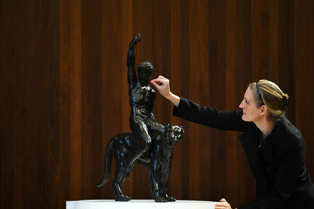 An employee removes fluff from 'Rothschild Bronzes', confirmed as the only surviving bronze sculpture by Michelangelo, during an event at The Royal Academy of Arts (RA) in London, Britain, November 14, 2018. REUTERS/Dylan Martinez