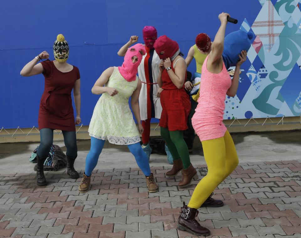 Members of the punk group Pussy Riot, including Nadezhda Tolokonnikova in the blue balaclava and Maria Alekhina in the pink balaclava, stage a protest performance in Sochi, Russia, about 30km (21miles) from where the Winter Olympics are being held, on Wednesday, Feb. 19, 2014. The group was attacked by about a dozen Cossack militiamen and other security officers almost immediately as they ran out of a nearby restaurant. (AP Photo/Morry Gash)