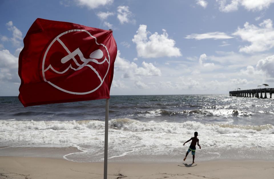 A boy plays on the beach as a No Swimming flag flies, Saturday, Aug. 31, 2019, in Lake Worth, Fla. Hurricane Dorian is bearing down on the northwestern Bahamas as a Category 4 storm. Forecasters say Dorian is then expected to go up the Southeast coastline. (AP Photo/Lynne Sladky)