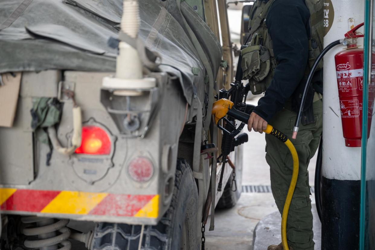 <span>An IDF soldier fills a Hummer with gas at a station near the Gaza border in southern Israel, on 19 November 2023.</span><span>Photograph: Alexi J Rosenfeld/Getty Images</span>