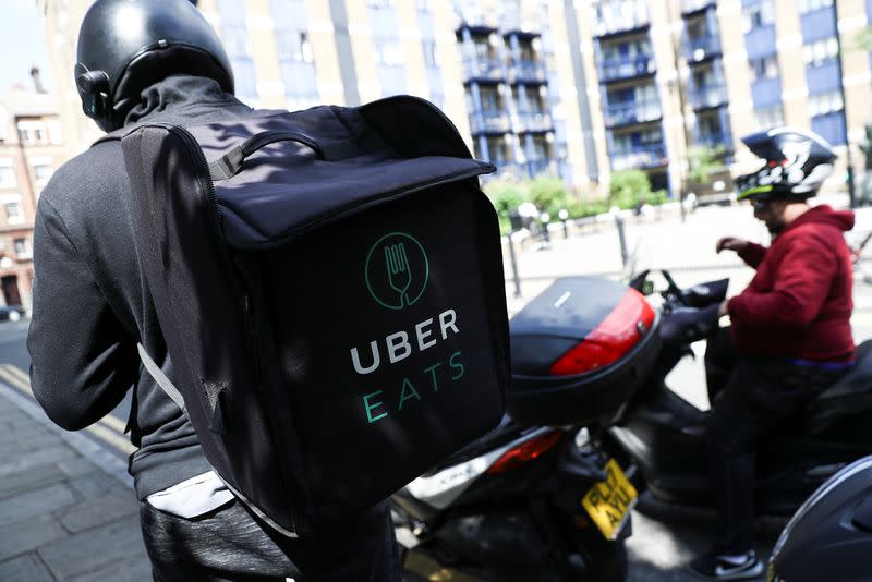 A scooter driver prepares to delivery an Uber Eats food order in London