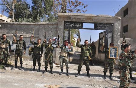 Soldiers loyal to Syria's President Bashar al-Assad raise their weapons while carrying pictures of him at Sbeineh town, southern Damascus, after they took control of it from rebel fighters last week, in this handout photograph distributed by Syria's national news agency SANA on November 15, 2013. REUTERS/SANA/Handout via Reuters