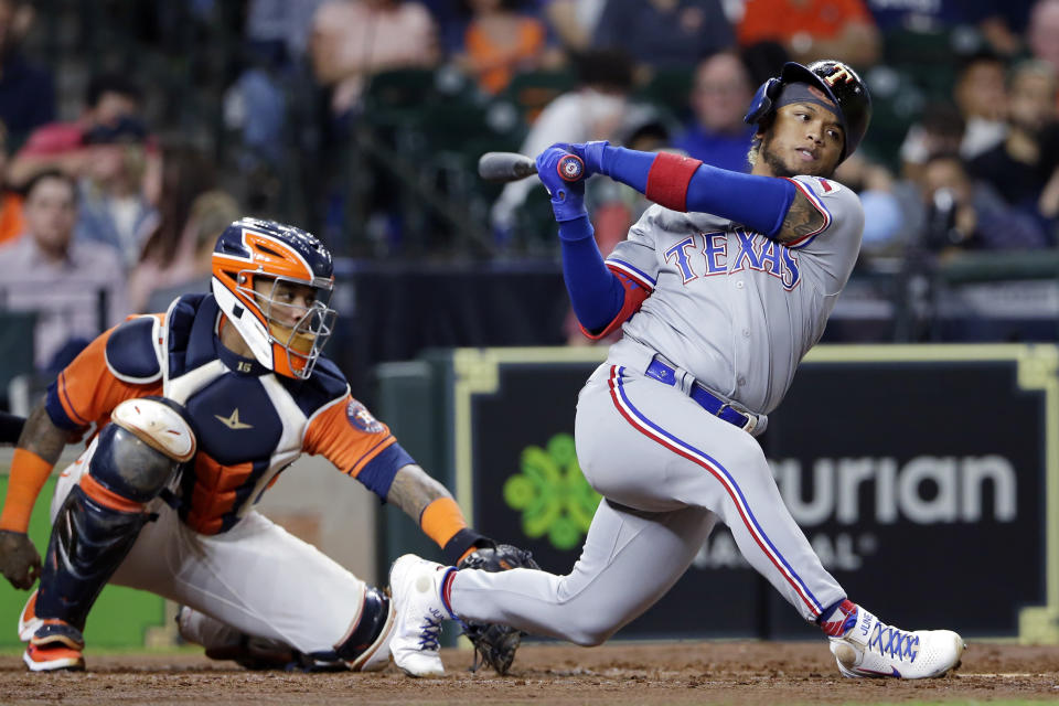 Texas Rangers' Willie Calhoun, right, loses his helmet as he strikes out swinging in front of Houston Astros catcher Martin Maldonado, left, during the fifth inning of a baseball game Friday, May 14, 2021, in Houston. (AP Photo/Michael Wyke)