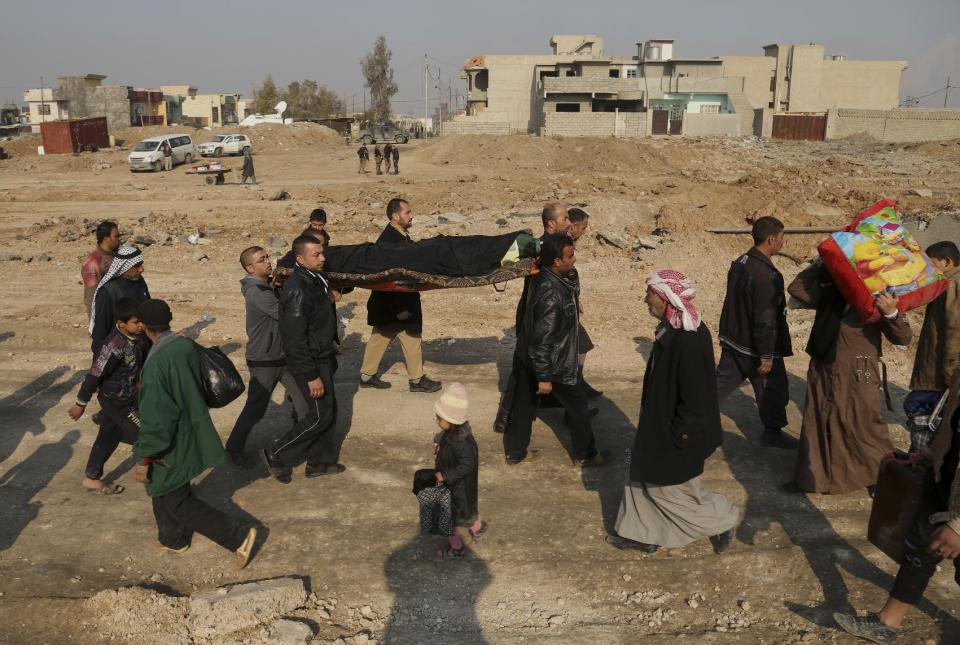 A victim killed by Islamic State militia bombing is taken for burial by displaced Iraqis, who fled the fighting between Iraqi security forces and Islamic state group, returning to their homes in the eastern side of Mosul, Iraq, Wednesday, Jan. 4, 2017. (AP Photo/ Khalid Mohammed)