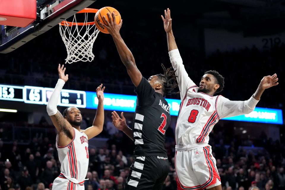 Cincinnati Bearcats guard Jizzle James (2) rises to the basket as Houston Cougars guard Mylik Wilson (8) defends in the second half of an NCAA college basketball game between the Houston Cougars and the Cincinnati Bearcats, Saturday, Feb. 10, 2024, at Fifth Third Arena in Cincinnati.