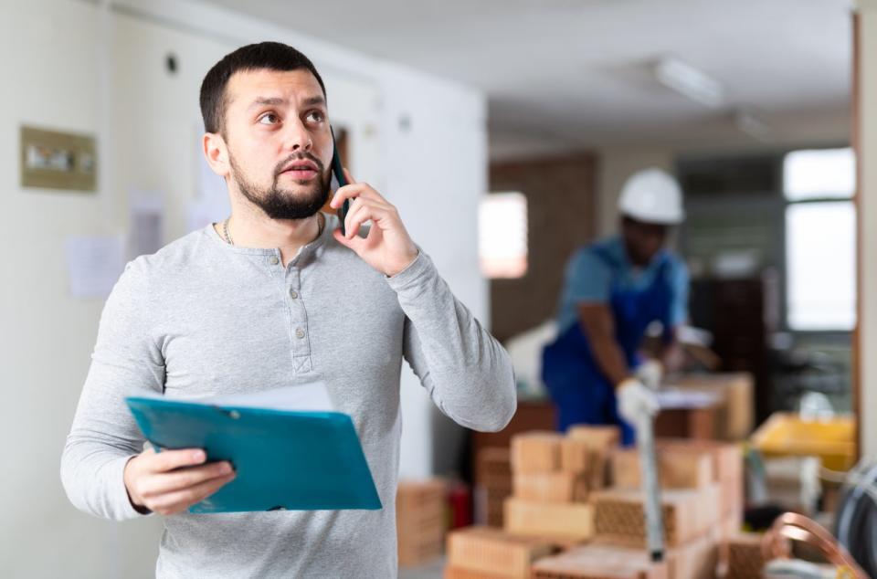 contractor talking on phone at construction site 