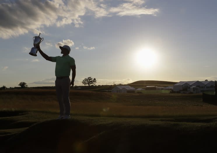 Brooks Koepka holds up the U.S. Open championship trophy as the sun falls on Erin Hills. (AP)