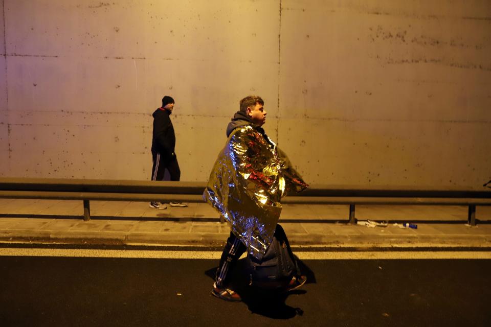 A passenger walks on a road after a train collision near Tempe, Greece, about 235 miles north of Athens.