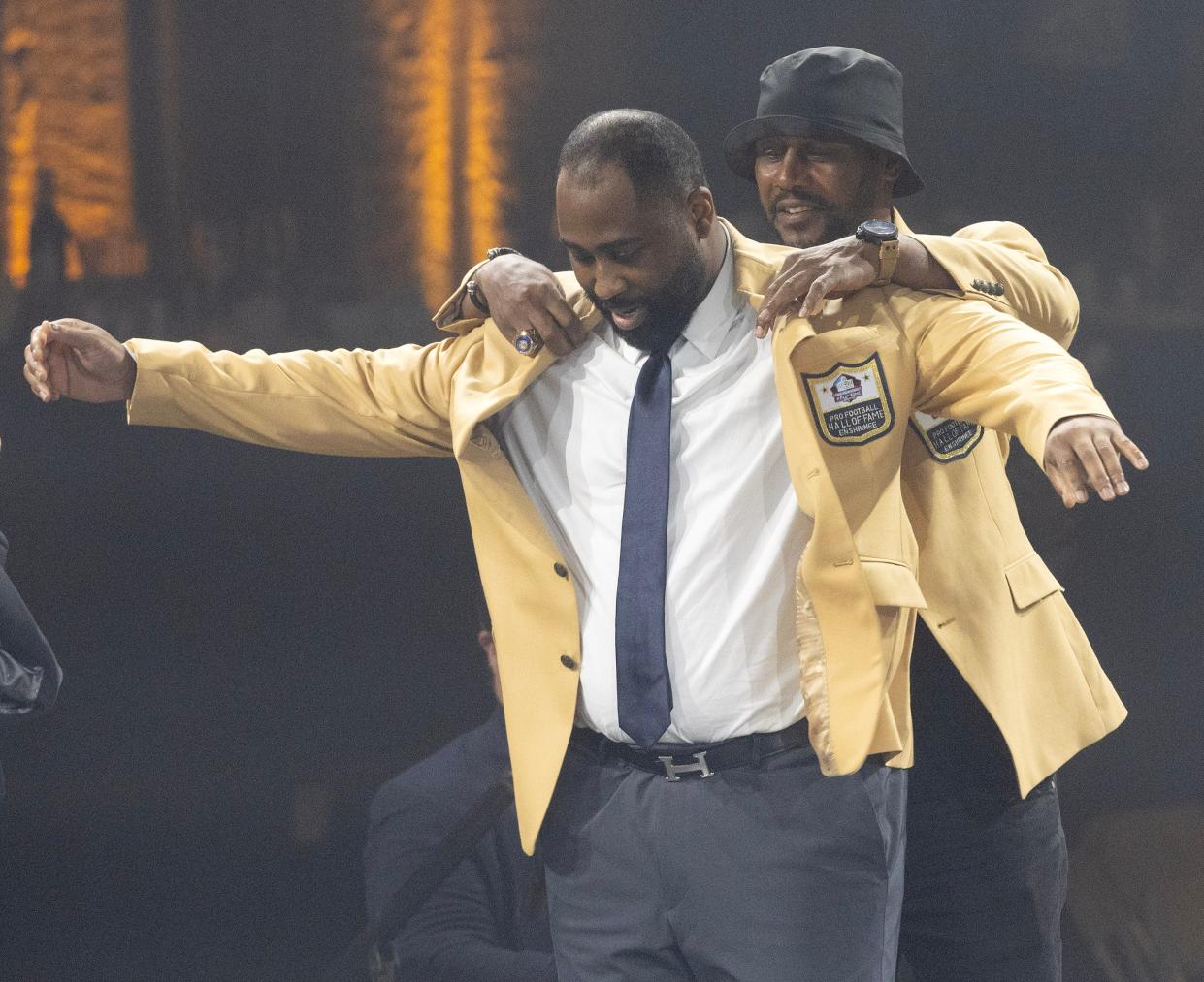 Darrell Revis is helped into his gold jacket by Hall of Famer Ty Law Friday in Canton.