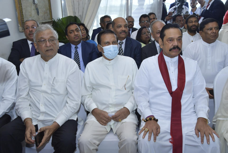 In this photo provided by Sri Lankan President's Office, lawmaker Lakshman Kiriella, left, former president Maithripala Sirisena, center and former prime minister Mahinda Rajapaksa, right attend the swearing in ceremony of Sri Lanka's newly elected president Ranil Wickremesinghe, in Colombo, Sri Lanka, Thursday, July 21, 2022. (Sri Lankan President's Office via AP)