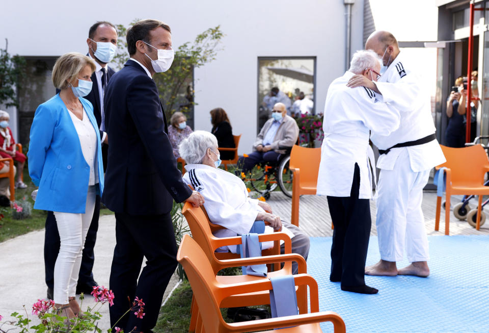 French President Emmanuel Macron, 2nd left, and Junior Minister of Autonomy Brigitte Bourguignon, left, meet residents at the 'La Bonne Eure' nursing home as they practicing martial arts in Bracieux, central France, Tuesday, Sept. 22, 2020. For the first time in months, virus infections and deaths in French nursing homes are on the rise again. (Yoan Valat/Pool Photo via AP)