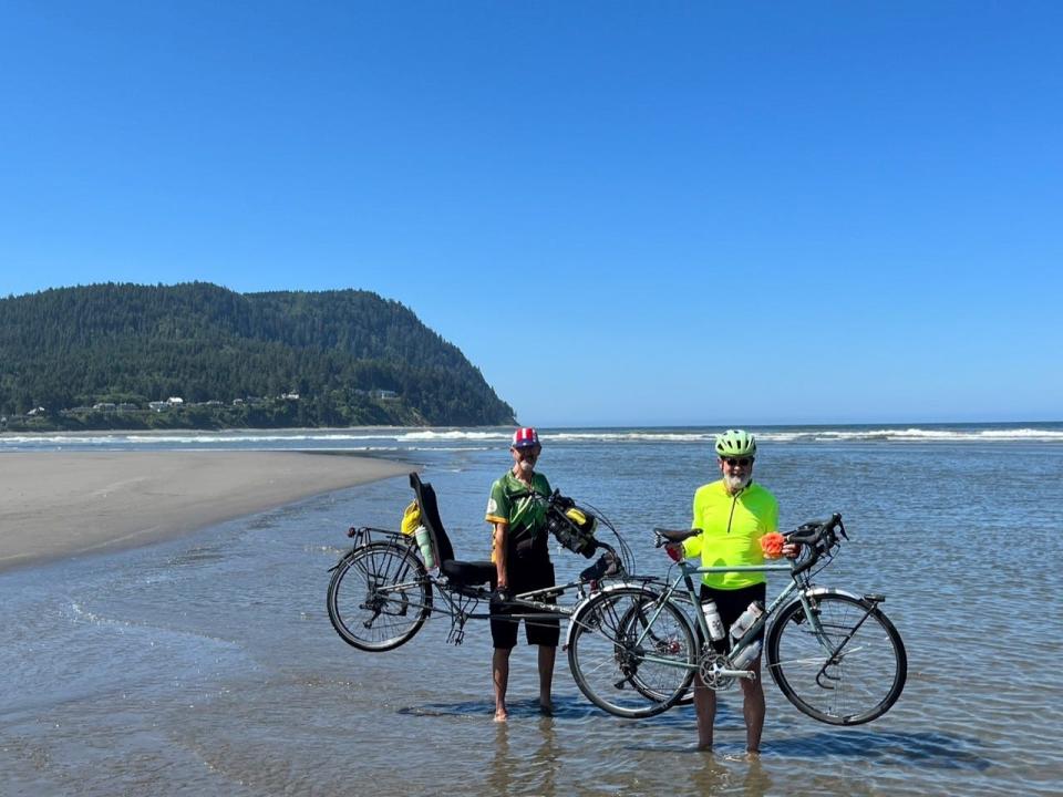 Brothers Ed, left, and John Chimahusky lift their bikes in celebration at the Pacific Ocean on July 26.