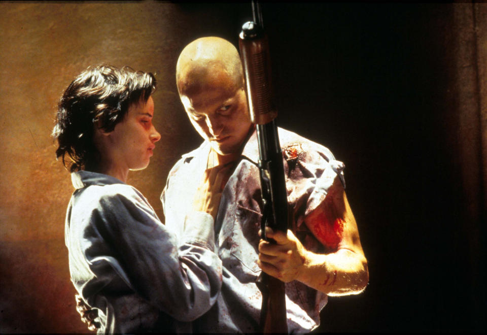 A bald man and his young lover stare longingly at a shotgun