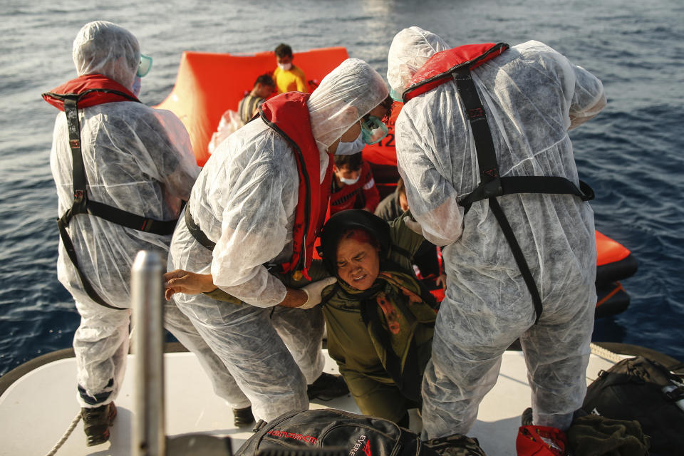 Turkish coast guard officers wearing protective gear to help prevent the spread of coronavirus, carry a woman off a life raft during a rescue operation in the Aegean Sea, between Turkey and Greece, Saturday, Sept. 12, 2020. Turkey is accusing Greece of large-scale pushbacks at sea — summary deportations without access to asylum procedures, in violation of international law. The Turkish coast guard says it rescued over 300 migrants "pushed back by Greek elements to Turkish waters" this month alone. Greece denies the allegations and accuses Ankara of weaponizing migrants. (AP Photo/Emrah Gurel)