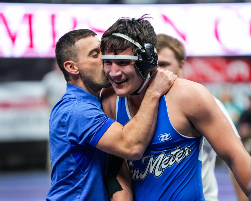 Van Meter’s Jackson Boese gets a kiss from his coach after defeating Clarinda’s Karson Downey in overtime at 182 pounds during the quarterfinals of the Class 2A of the Iowa high school state wrestling tournament at Wells Fargo Arena in Des Moines on Thursday, Feb. 16, 2023.